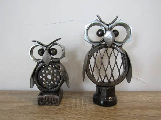 Deux sculptures de chouettes fabriquées par Jérôme Petelot à partir de métaux de récupération. Celle de gauche est deux fois plus petite que celle de droite.